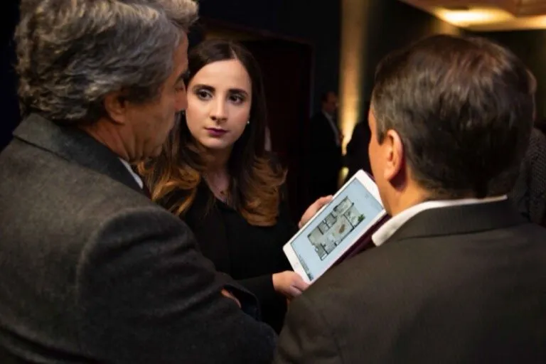 Invitados revisando el plano de un apartamento en tablet durante el evento